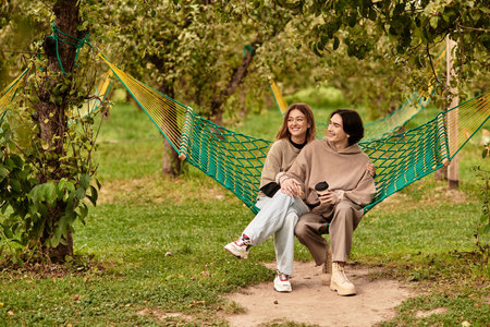 Loving pair relaxes in a hammock surrounded by lush greenery, sharing a joyful time together.