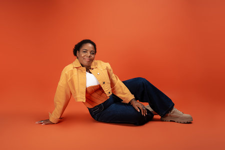 A confident plus size african american woman showcases her trendy autumn outfit in a vibrant studio.