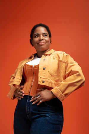 A confident woman models a trendy autumn outfit, celebrating fashion and diversity in a studio.