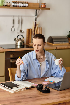 In a bright kitchen, a young man works thoughtfully, sipping coffee and writing notes.
