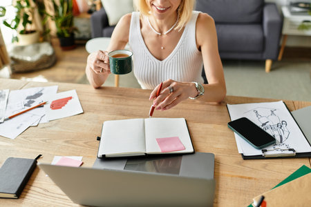 An adult woman relaxes at home, sipping coffee and writing in her notebook while surrounded by art.のeditorial素材