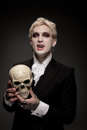 Young man showcases an impressive Halloween costume, holding a skull while dressed for the occasion.