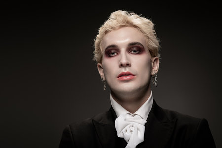 A young man showcases his stunning Halloween costume and dramatic makeup in a dark setting.の写真素材
