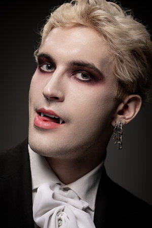 A handsome young man showcases his epic Halloween costume with dramatic makeup and vampire fangsの写真素材