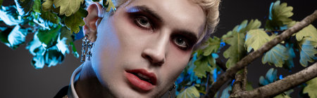 A young man dressed in a stunning Halloween costume stands amidst lush greenery, exuding charm.の写真素材