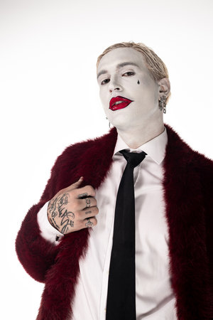 Handsome young man proudly displays his epic Joker costume during a Halloween event, full of spirit.