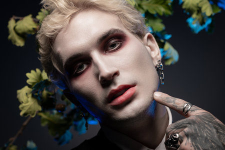 Young man shows off a creative Halloween costume with dramatic makeup and unique jewelry.の写真素材