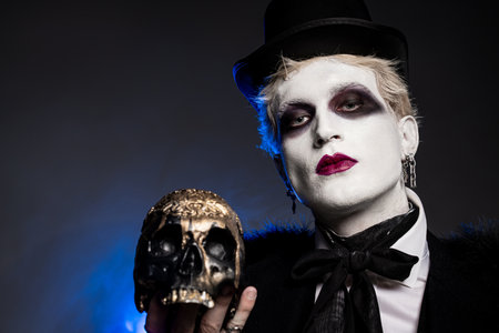 Handsome young man dons a striking Halloween disguise, holding a decorative skull in celebration.