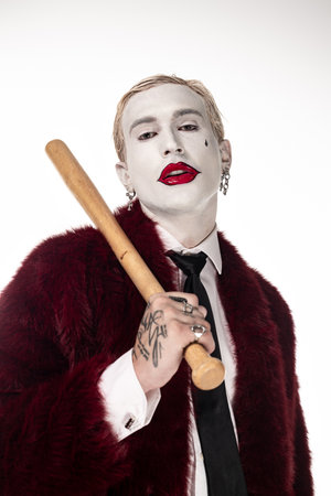 A young man showcases his impressive Joker costume complete with a wooden bat.