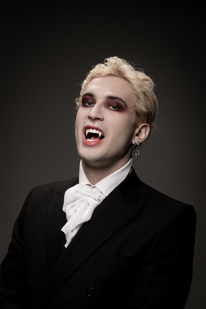 A charming young man in a fancy vampire costume joyfully celebrates Halloween.の写真素材