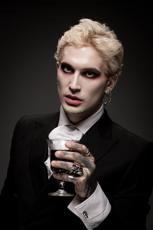 A stylish young man confidently shows off his detailed Halloween costume with a glass.