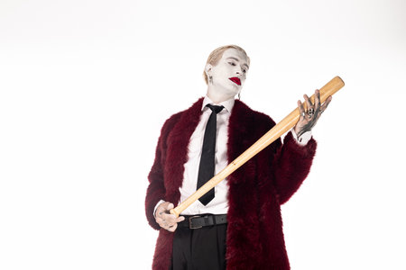 A handsome young man showcases his Joker costume this Halloween, holding a bat confidently.のeditorial素材