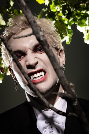 A young handsome man displays an impressive Halloween costume with fierce features under soft light.のeditorial素材