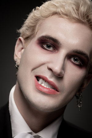Young man showcases an impressive Halloween costume with bold makeup, presenting a captivating look.