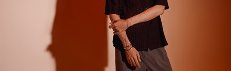 A handsome young man stands proudly in trendy attire against a warm backdrop, exuding style.の写真素材