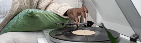 A stylish woman listens to vinyl records in her comfortable living room, bannerの写真素材