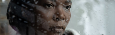 A woman lost in thought, feeling the weight of sadness behind rainy window, banner