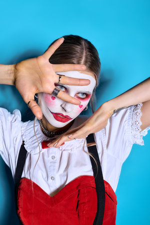A young woman poses with flair in a detailed Halloween costume, showcasing vibrant makeup and style.のeditorial素材