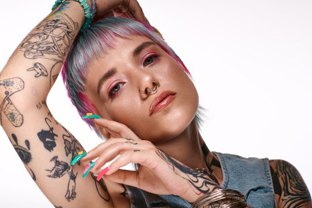 A young woman with short, colorful hair and tattoos expresses her unique style in a studio.の写真素材