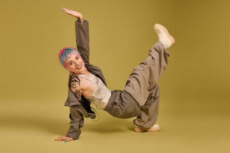 A young woman with vibrant short hair strikes a dynamic pose, radiating happiness in a studio.