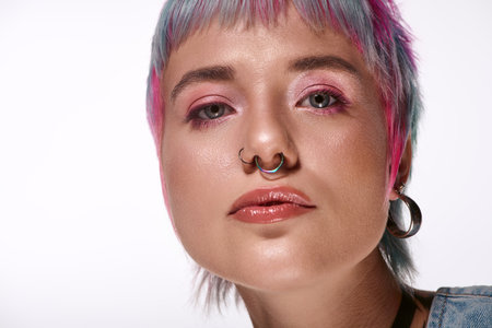 A confident young woman with short, colorful hair poses in a bright studio.