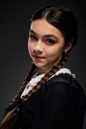 A girl in braids wears a Wednesday gothic dress, perfectly embodying the Halloween spirit.の写真素材