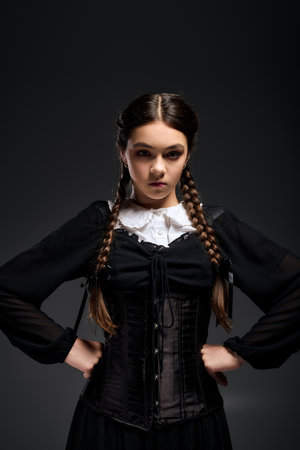 A girl with braided hair dons a gothic Wednesday dress, embodying a spooky character for Halloween.の写真素材
