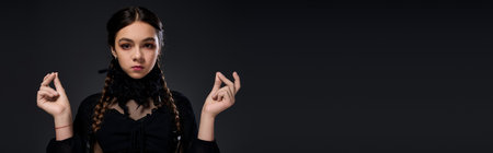 A girl dressed in a gothic style costume embodies a Wednesday character for Halloween festivities,...