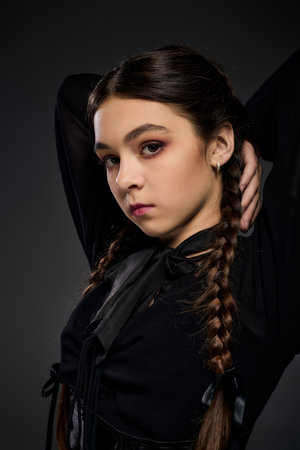 A child dressed in a gothic Wednesday costume poses dramatically, showcasing her braided hair.の写真素材
