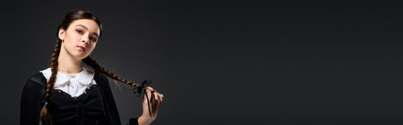 A girl in a gothic Wednesday costume with braids poses confidently for Halloween, banner