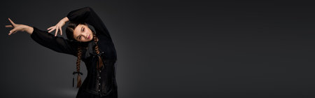 Young girl with braids showcases her gothic Wednesday costume inspired by a spooky character, bannerのeditorial素材