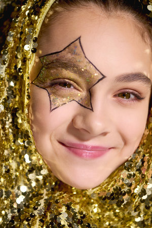 A girl in a star design shines among golden sequins, celebrating Halloween.の写真素材