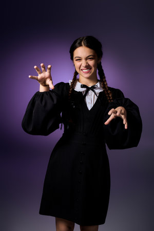 Child with braids wears a gothic costume, capturing the Wednesday character vibe with a playful pose.の写真素材
