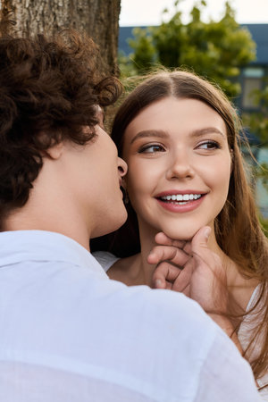 A curly-haired young man leans in to whisper sweet words to his beautiful partner in nature.のeditorial素材
