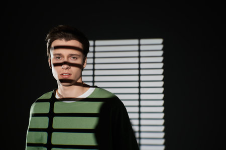 Young handsome man showcases modern youth culture with unique shadows and lighting.