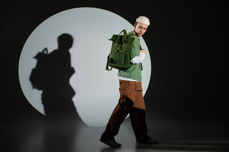 A trendy teen in a green backpack showcases youth style in an artistic scene.