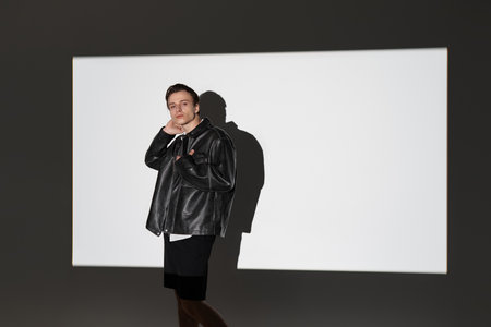 Youthful and stylish teenager showcases modern fashion, exuding confidence in a minimalist space.