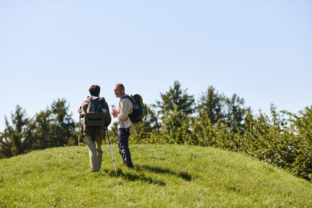 Active seniors enjoy a beautiful day of hiking amidst green hills and blue skies.の写真素材