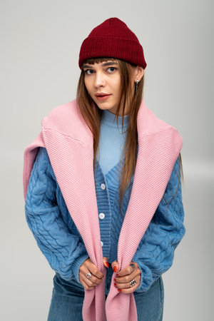 Young woman exudes warmth in colorful layers while playfully posing against a soft backdrop.の写真素材