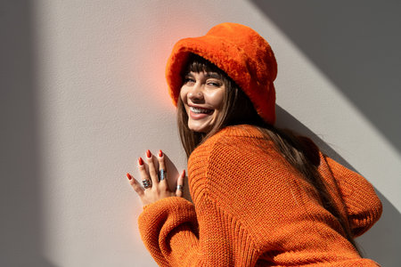 Beautiful young woman poses joyfully in warm, stylish attire, showcasing her vibrant personality.