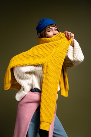 Youthful woman showcases her fashion sense with bold colors and playful poses in cozy attire.