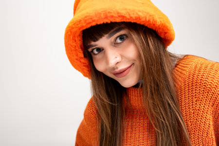 Young woman poses cheerfully in warm autumn fashion, radiating joy and style in cozy surroundings.の写真素材