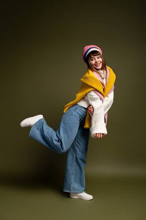 Warmly dressed woman showcases her playful side while smiling in cozy autumn surroundings.の写真素材