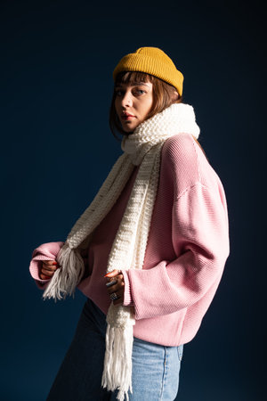 Vibrant young woman in warm attire poses against a dark background, radiating style and confidence.