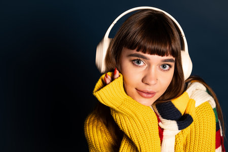 A young woman showcases her fashion sense in a vibrant sweater while enjoying music.