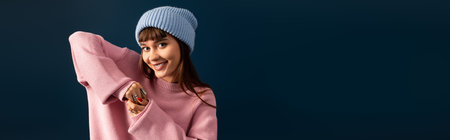 Vibrant young woman poses playfully in cozy autumn attire, exuding warmth and cheer.