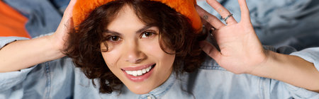Bright and fashionable young woman enjoys a moment of joy with her vibrant orange hat.の写真素材