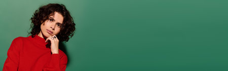 Stylish young woman poses confidently in a striking red outfit against a bold green backdropの写真素材