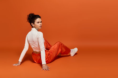 Fashionable young woman sits gracefully on the floor, showcasing her unique style in bright colors.の写真素材