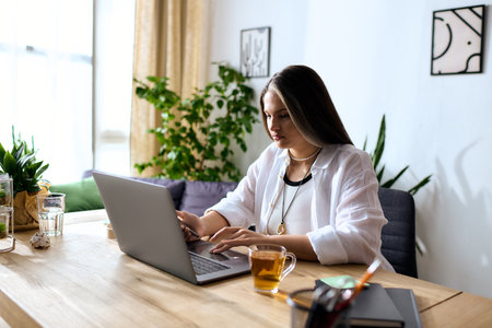 Woman with unique hair caused by with Waardenburg Syndrome works intently on her laptop at homeの写真素材